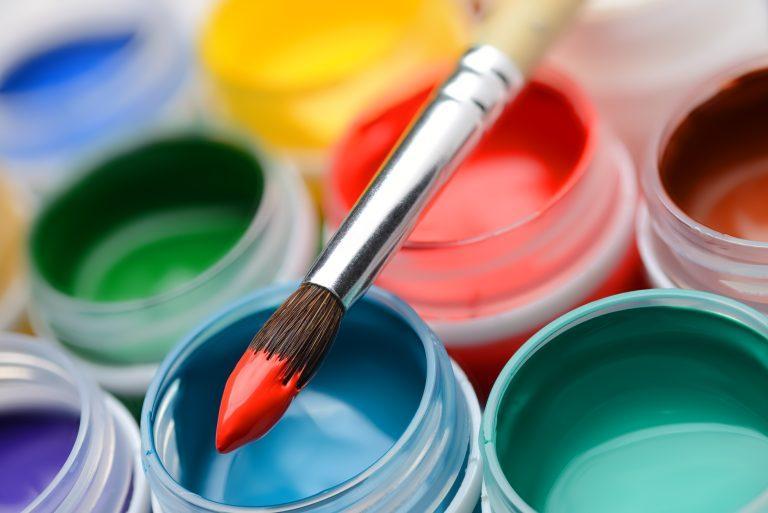 Different colors gouache paint jars set with paintbrush. Macro shot top view